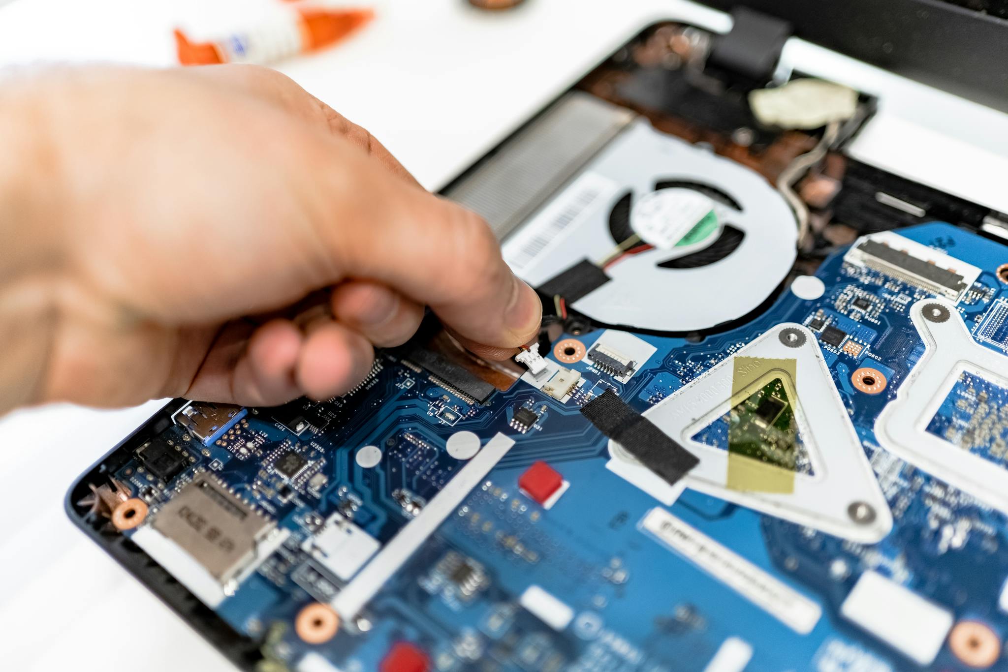 Close-up view of a hand fixing a computer motherboard showcasing technology and electronics repair.